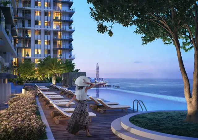 Beach Isle tower facade lit at dusk above its infinity pool deck facing the sea
