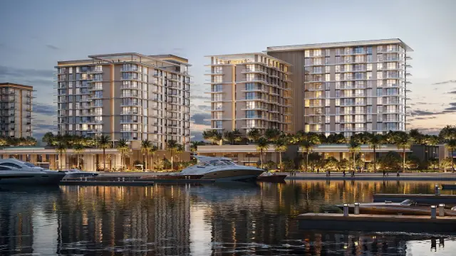 Marina Place residential buildings lit at dusk above the water of Rashid Yachts and Marina, with yachts moored in front