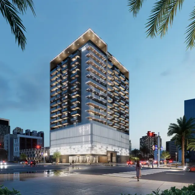 Taraf 3 Residence illuminated at dusk above its retail podium in JVC
