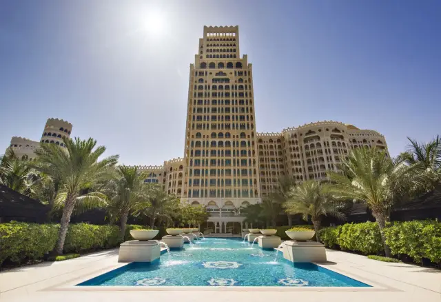 البرج المركزي لوالدورف أستوريا رأس الخيمة فوق أشجار النخيل وبركة النافورة